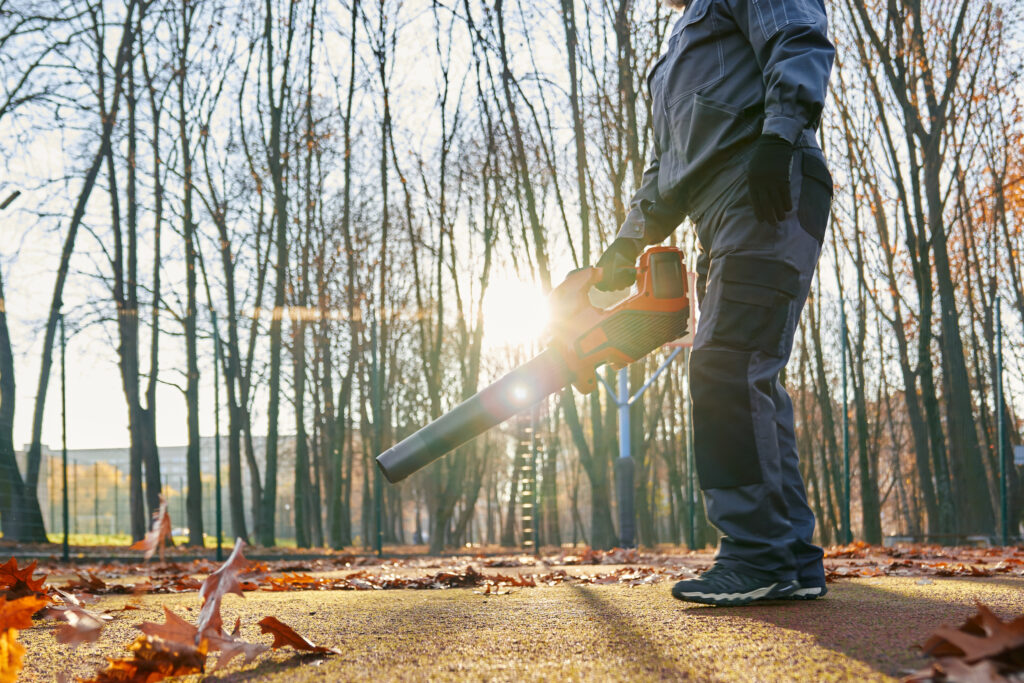 unrecognizable maintenance worker with leaf blower in autumn.