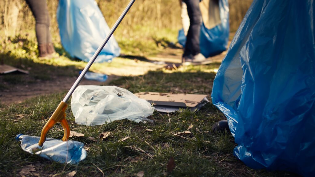 volunteer using tongs tool to collect trash and plastic waste from the woods volunteer using tongs tool to collect trash and plastic waste from the woods